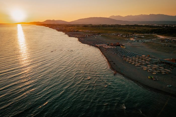 The sun is setting over a beach with umbrellas
